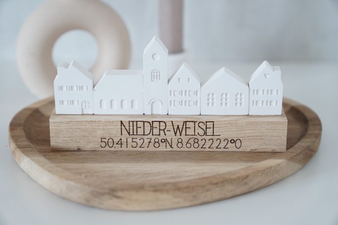 Weiße Gebäude auf einer Holzplatte mit der Beschriftung „NIEDERWEISSEL“.